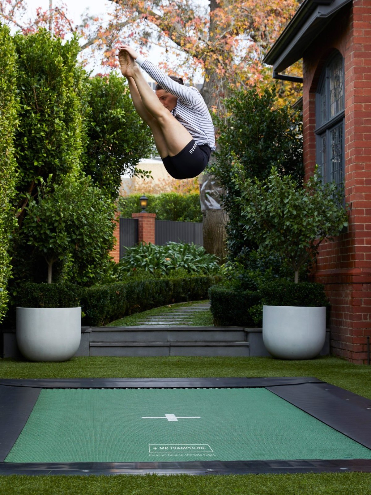 Person jumping on a trampoline in a backyard